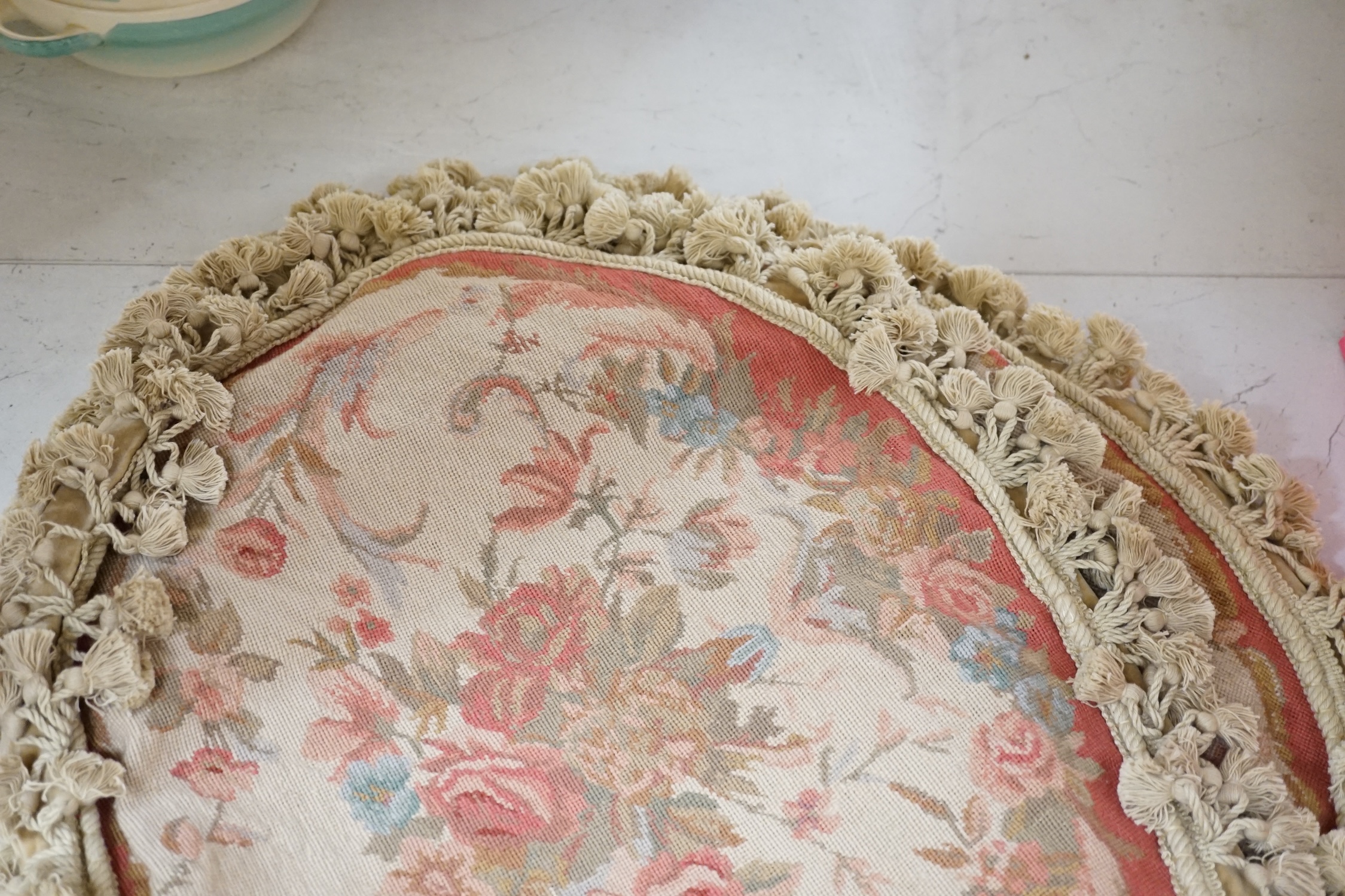 Four 20th century oval floral needleworked cushion covers with tasselled edging, 57cm wide